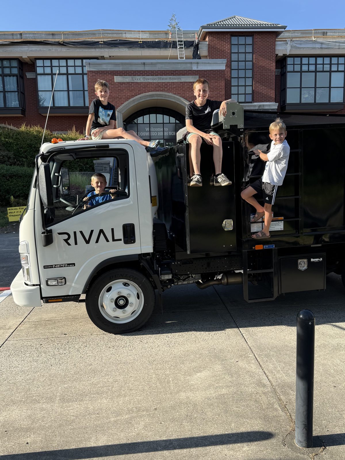 Three young boys posing on the Rival truck outside Lake Oswego High School